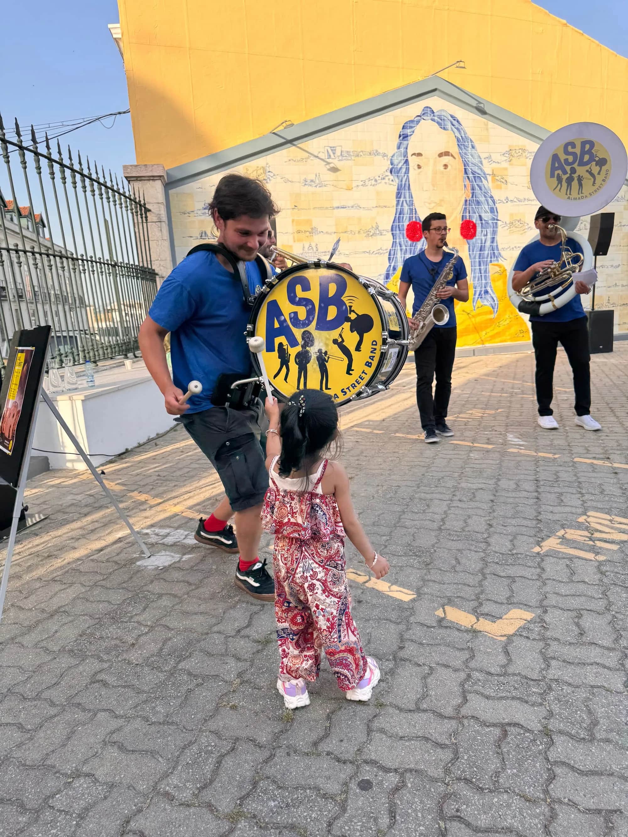 A small child looking at the ASB bass drum in the street