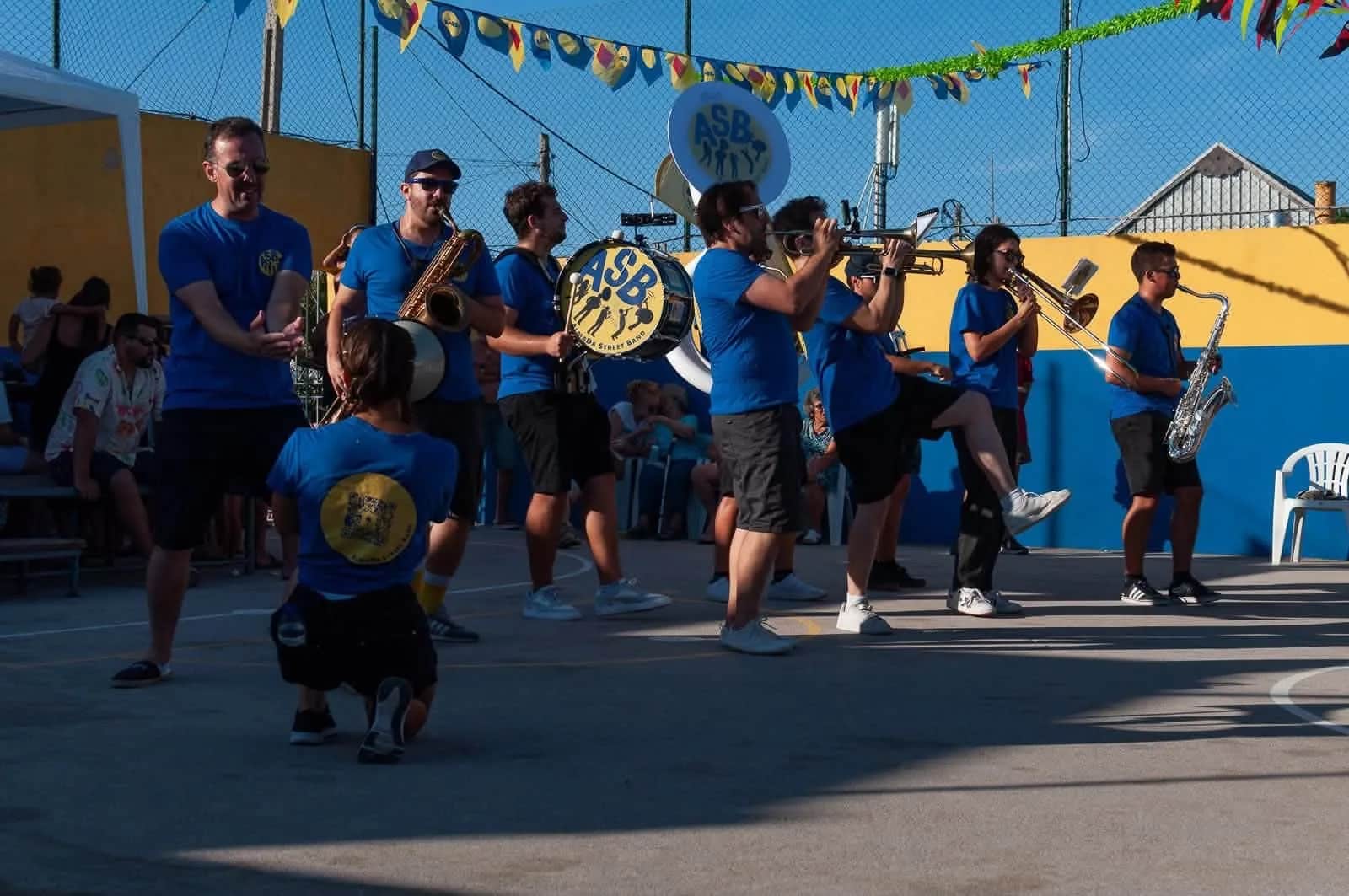 A banda a tocar numa rua enfeitada com bandeirinhas de arraial